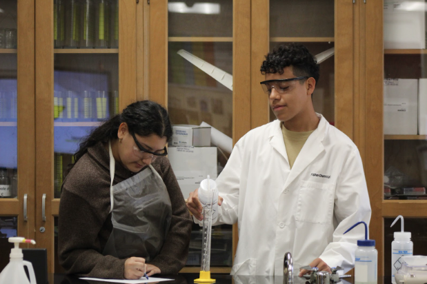 FUTURE SCIENTISTS TAKE ACTION Junior Axel Castro demonstrates lab skills while gathering petition signatures to bring AP Chemistry to the course catalog for next fall.